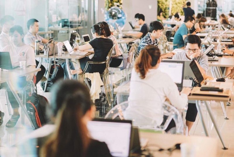 Photo of several people working in a modern, open-office workspace.